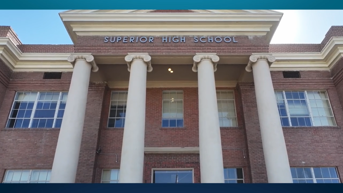 Superior high school building facade from below, red brick walls and white ionic columns