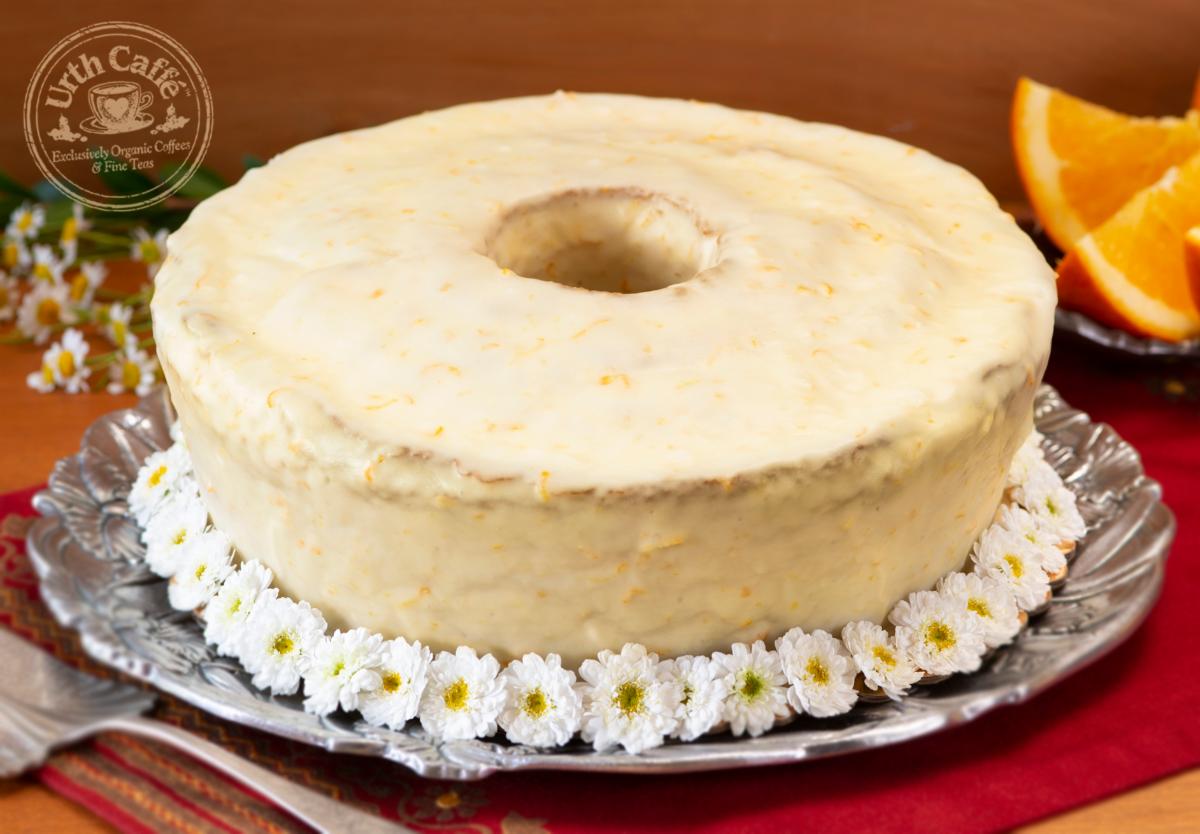 Photo of Urth Caffé Orange Pound cake, whole with garnish and sliced oranges, on a silver platter. 