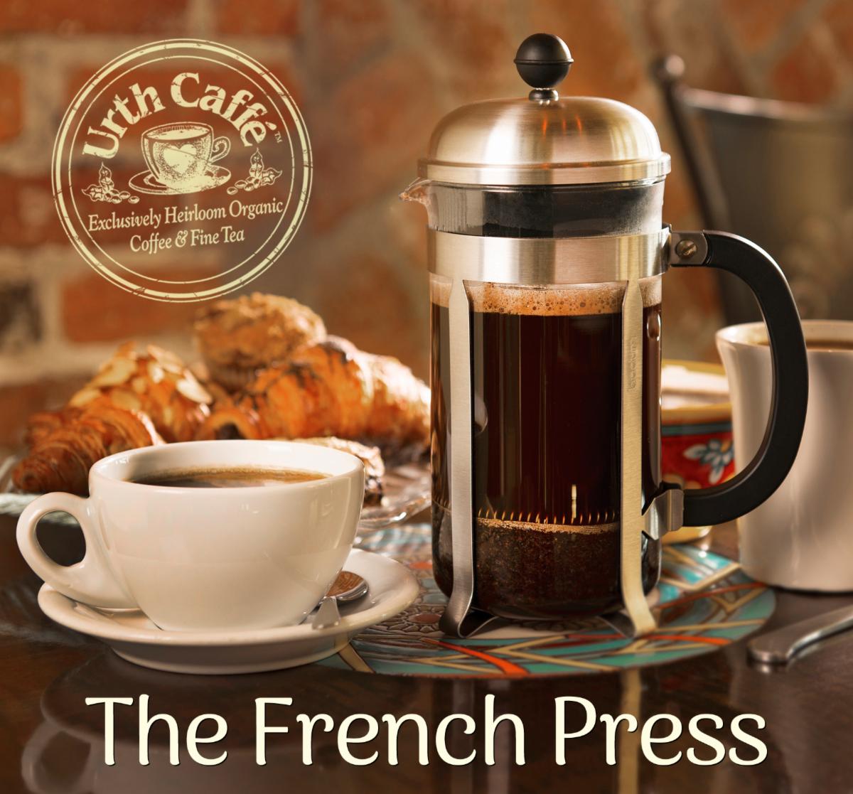 Photo of Urth french press coffee maker, with a ceramic white coffee cup and saucer, with croissnat in the background. With Urth logo and text.