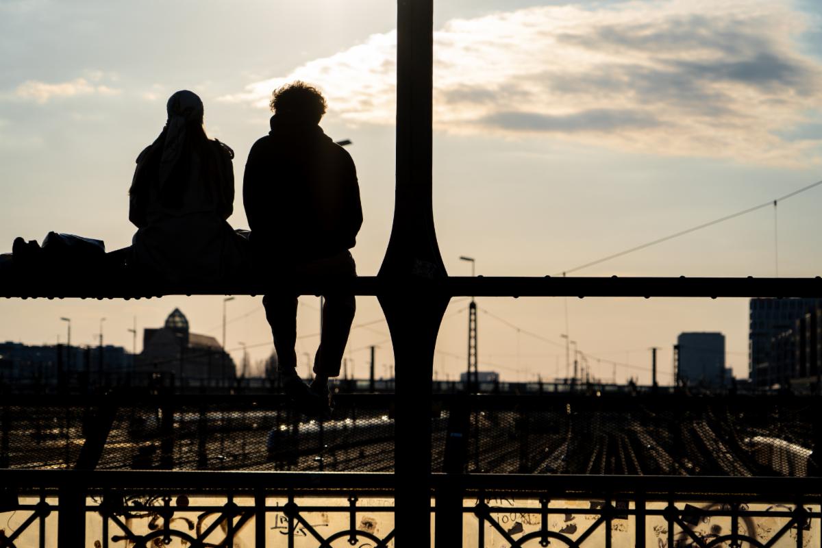Silhouette of a couple talking at sunset on the train tracks. Silhouette of two people chatting on a bridge over the train tracks. Sunset in Munich Germany.