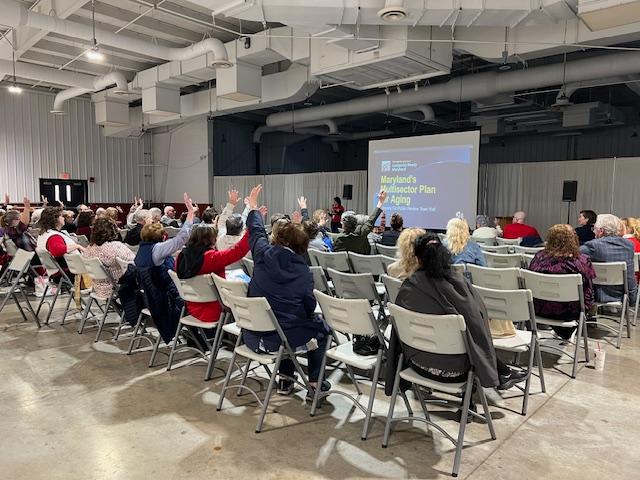 Several audience members at the Salisbury town hall are raising their hands as they participate in questions on Longevity Ready Maryland.