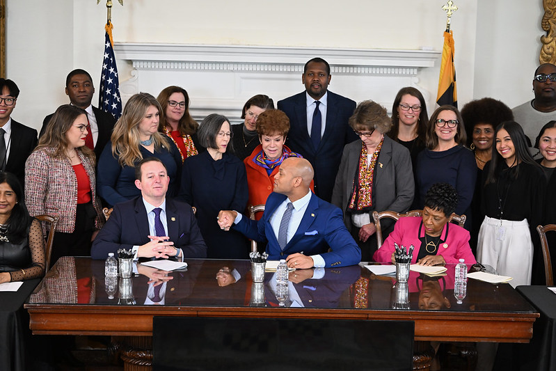 Photo of Governor Moore acknowledging MDOA Secretary Roques after signing MDOA bills into law.