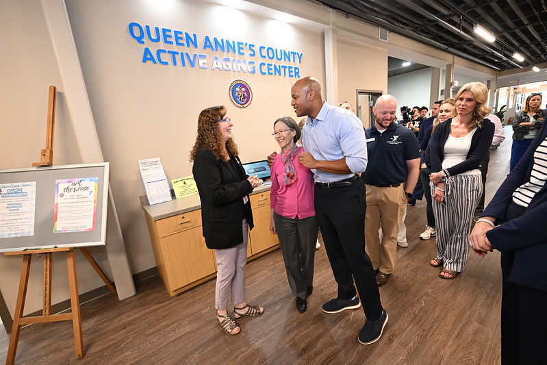 Picture of Governor Moore with his arm around Secretary Roques during a visit to the Queen Anne's County YMCA and Active Aging Center. Photo Credit: Office of Gov. Moore
