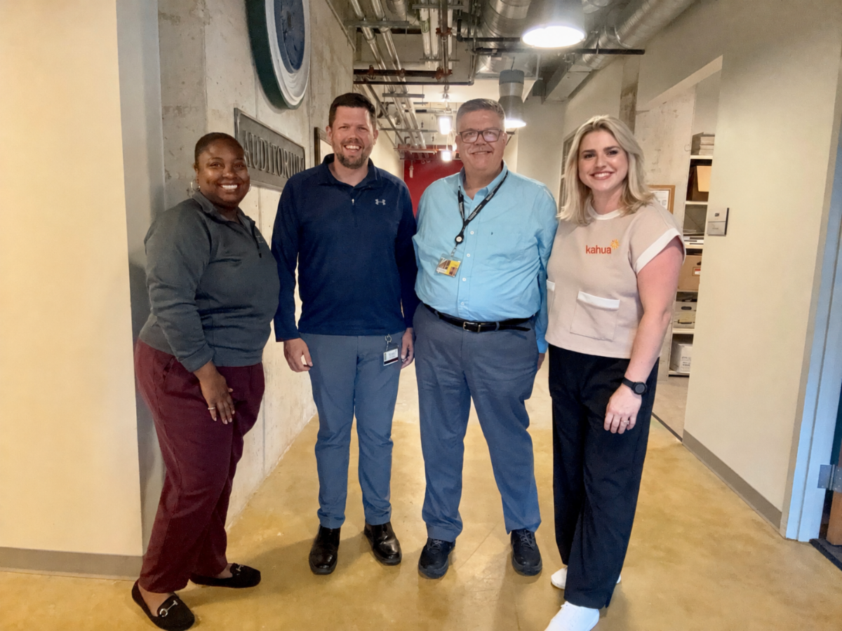 Four people posing for a picture in a hallway