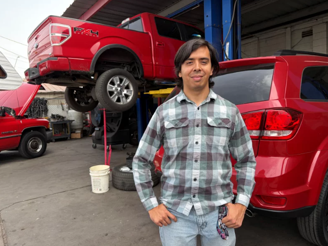 Person standing in front of a car shop