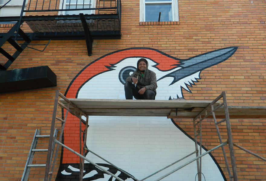 Man sitting in front of a bird mural