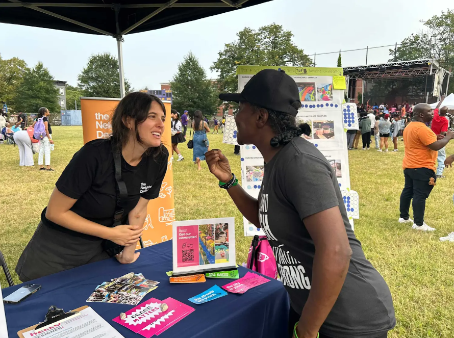 Two people talking at an outdoor tabling event