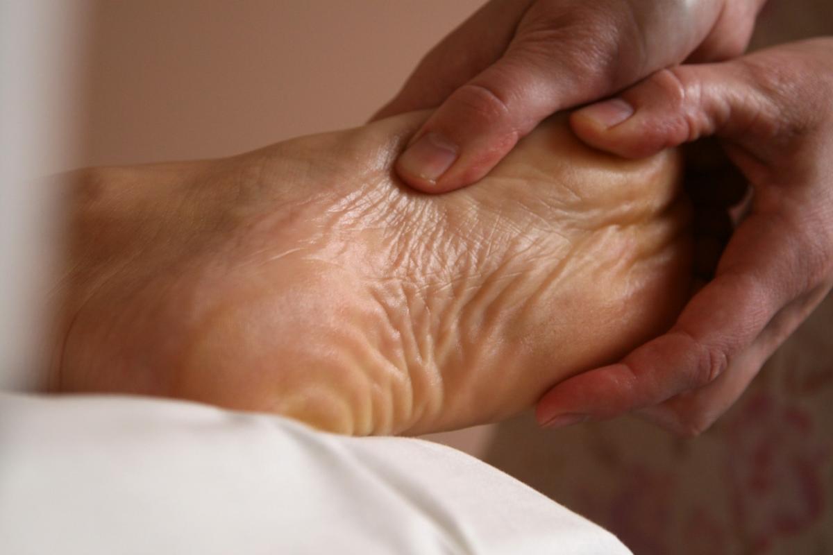 The hand of a healthcare worker inspects a foot. 