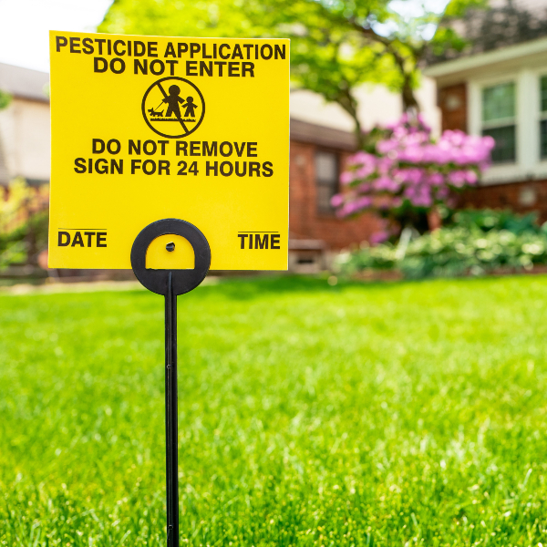 A yellow lawn sign reading pesticide application do not enter. Do not remove sign for 24 hours.