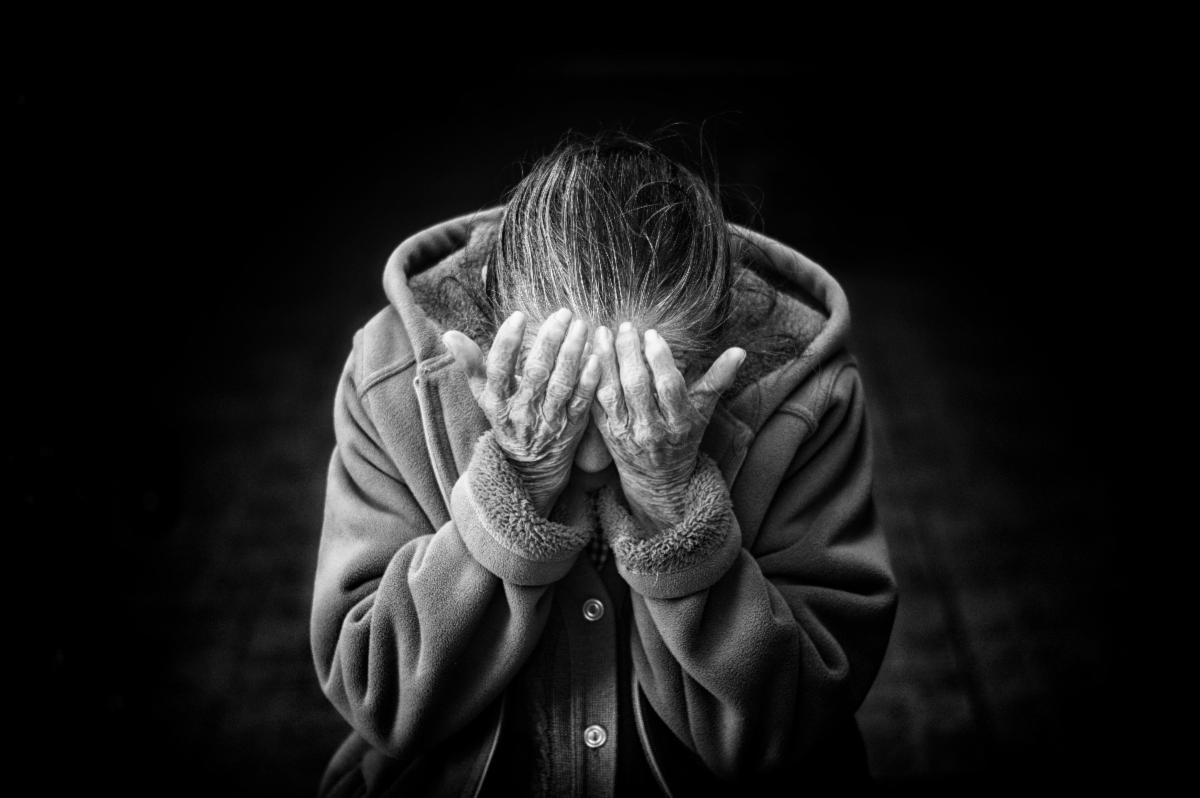 Older woman holding her head in her hands
