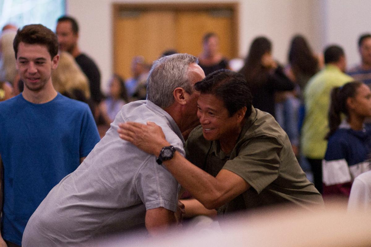 Two men hugging with people in the background