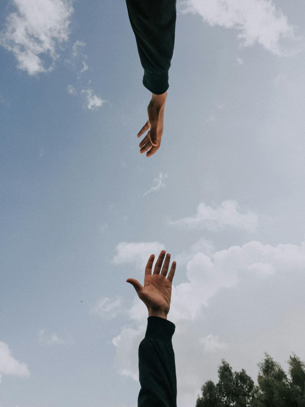 Hands reaching up to each other in the sky