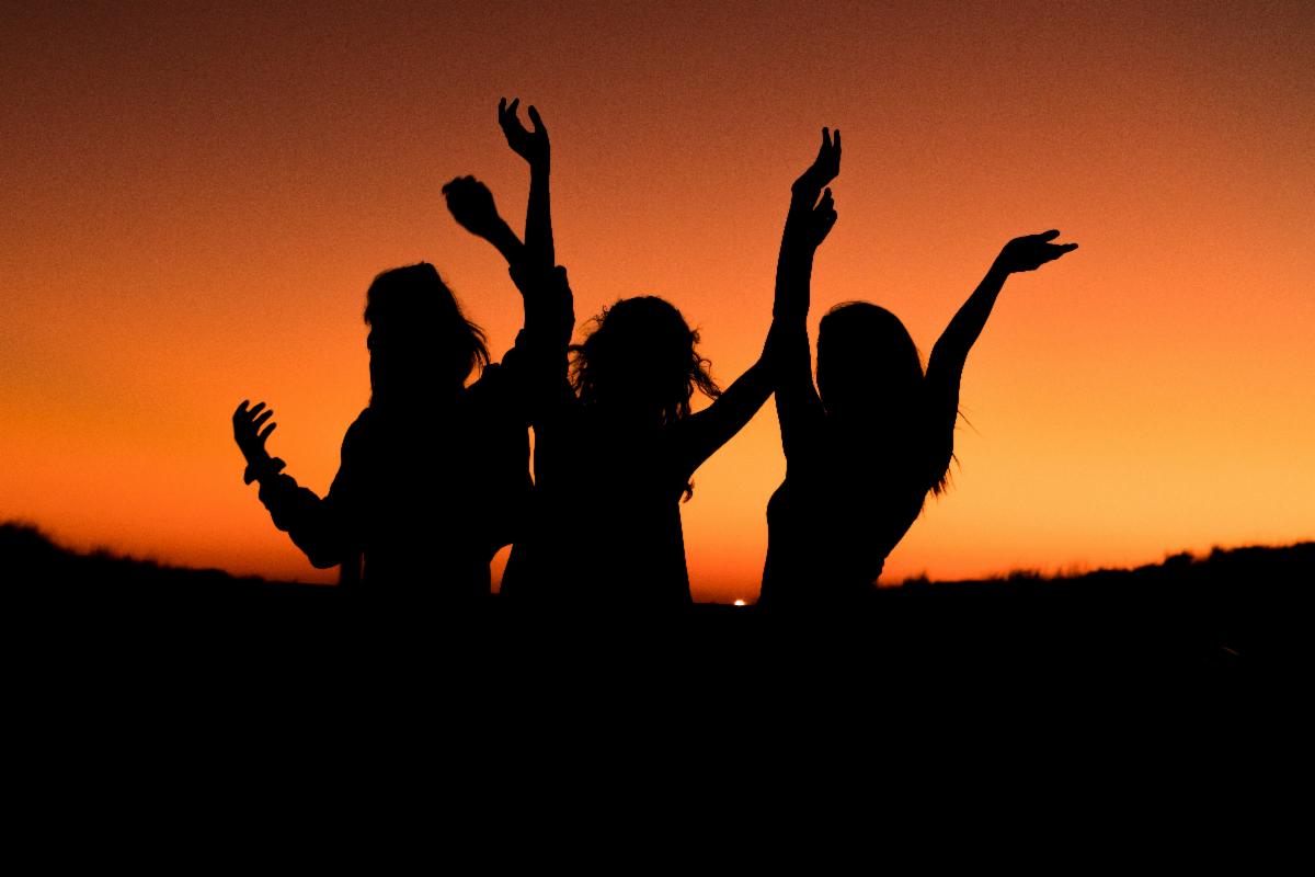 Three women silhouette with a sunset background