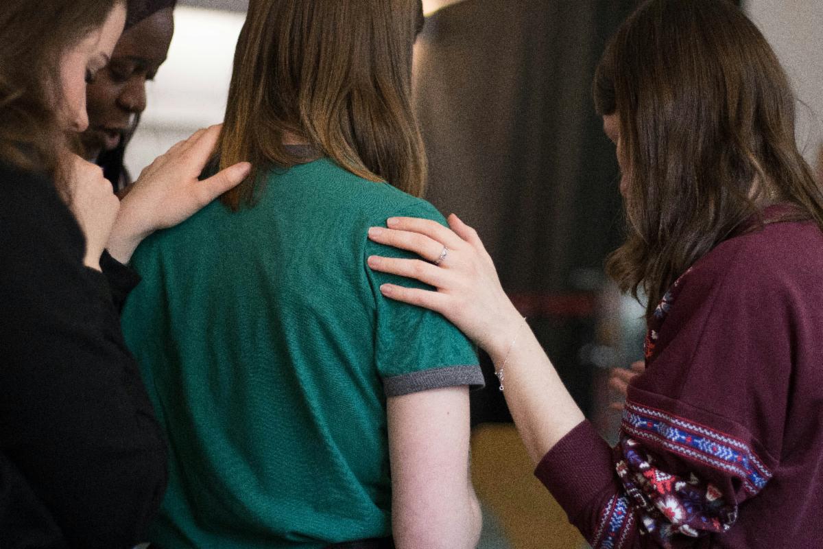 Women in a group laying hands on one of them