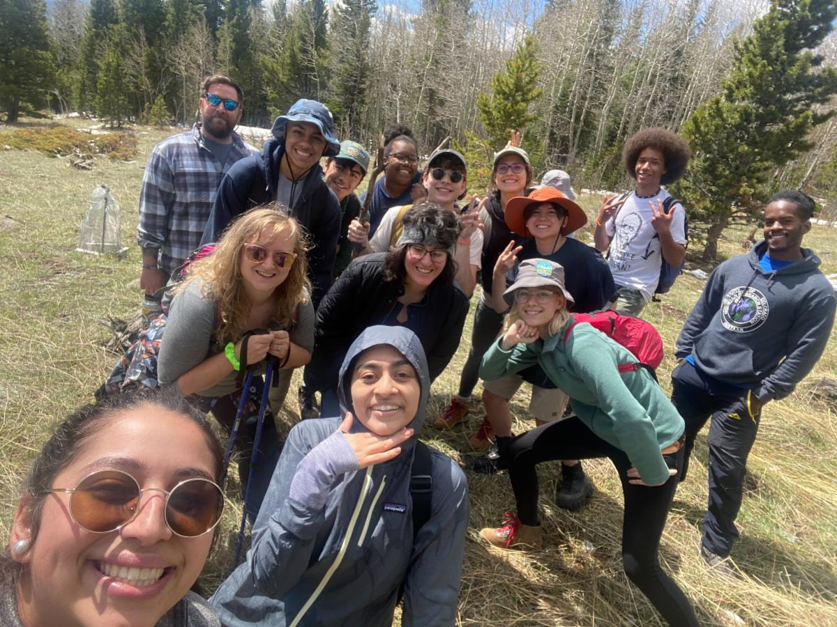 A group of people in hiking clothes pose together in a field