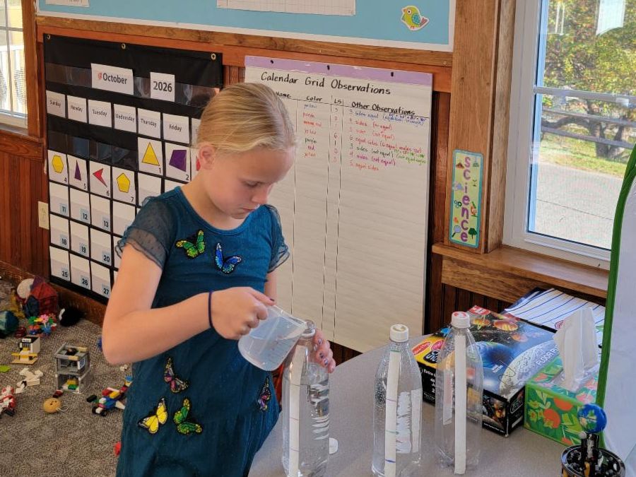A third grader pours liquid in a tube as part of number corner