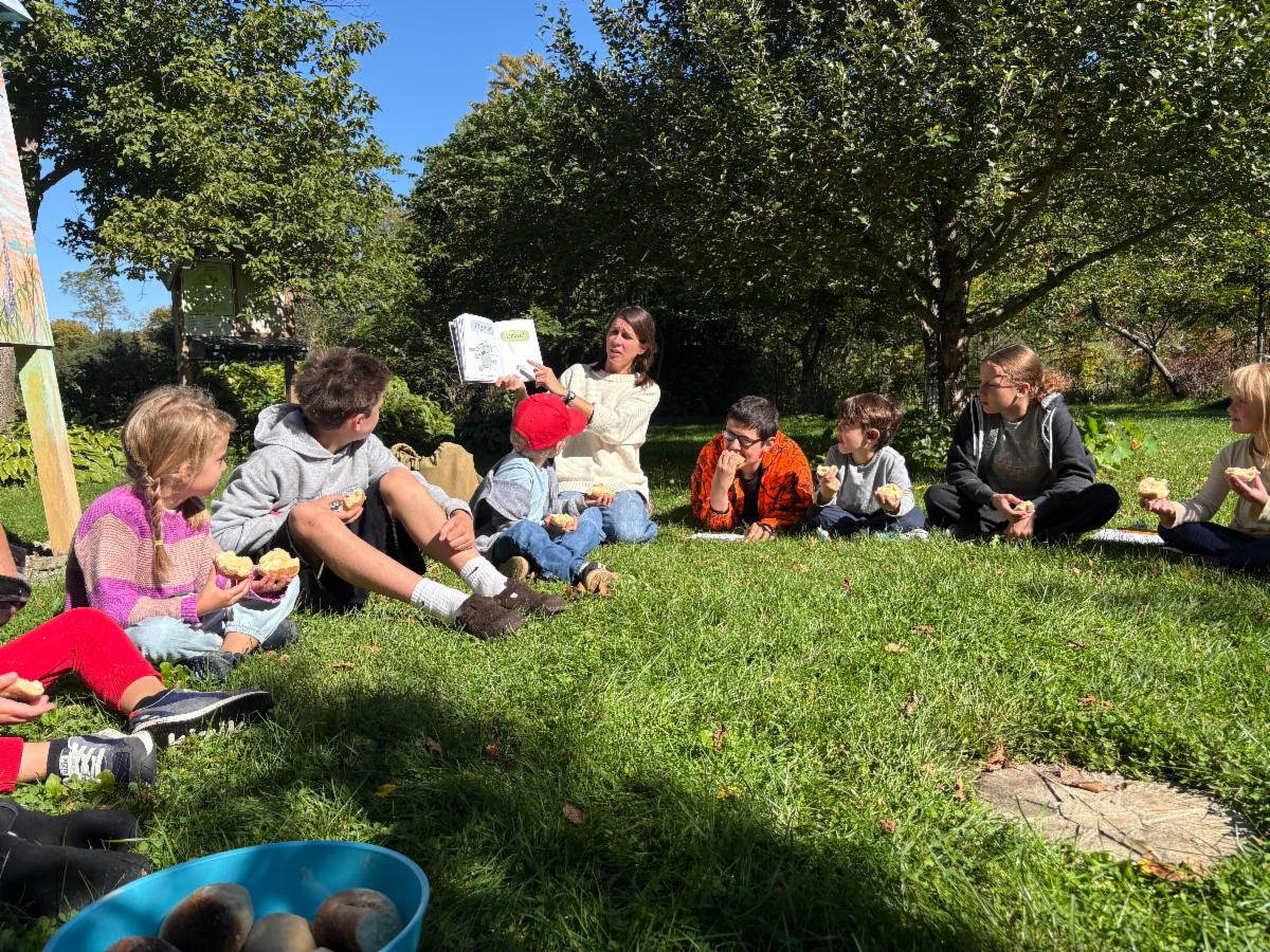 Kindergartners and 8th graders enjoy a read aloud outside