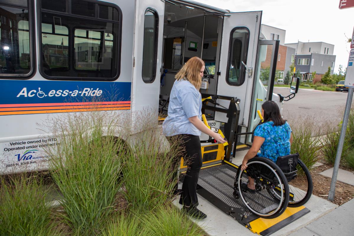 Woman in a wheelchair getting onto lift on a access-a-ride vehicle