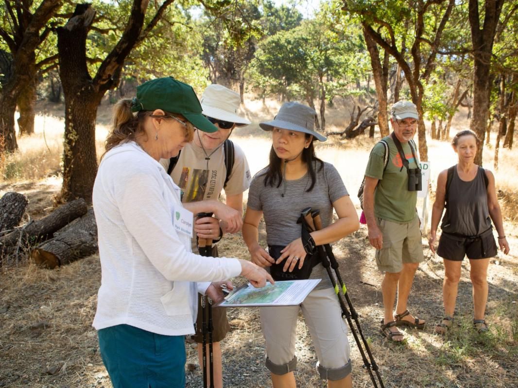 Hikers listen as a volunteer points to their location on a map