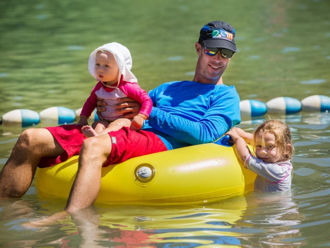 Kids and dad float on a tube in the water