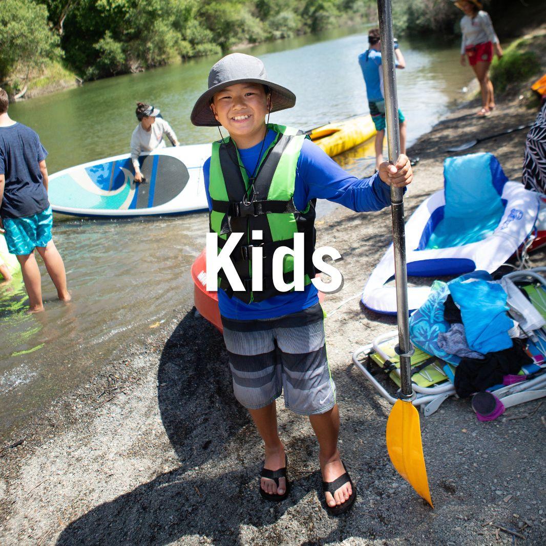 Boy with kayak and paddle on beach text superimposed reads kids