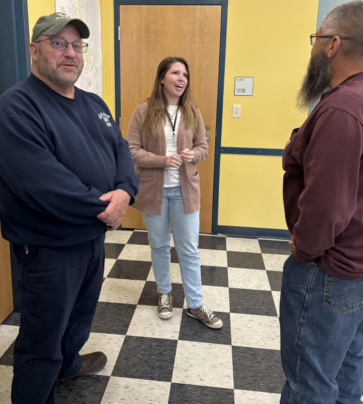 ChatGPT said:
three people standing and talking in a hallway with yellow walls and checkered floor appearing to share a lighthearted conversation during a workshop break