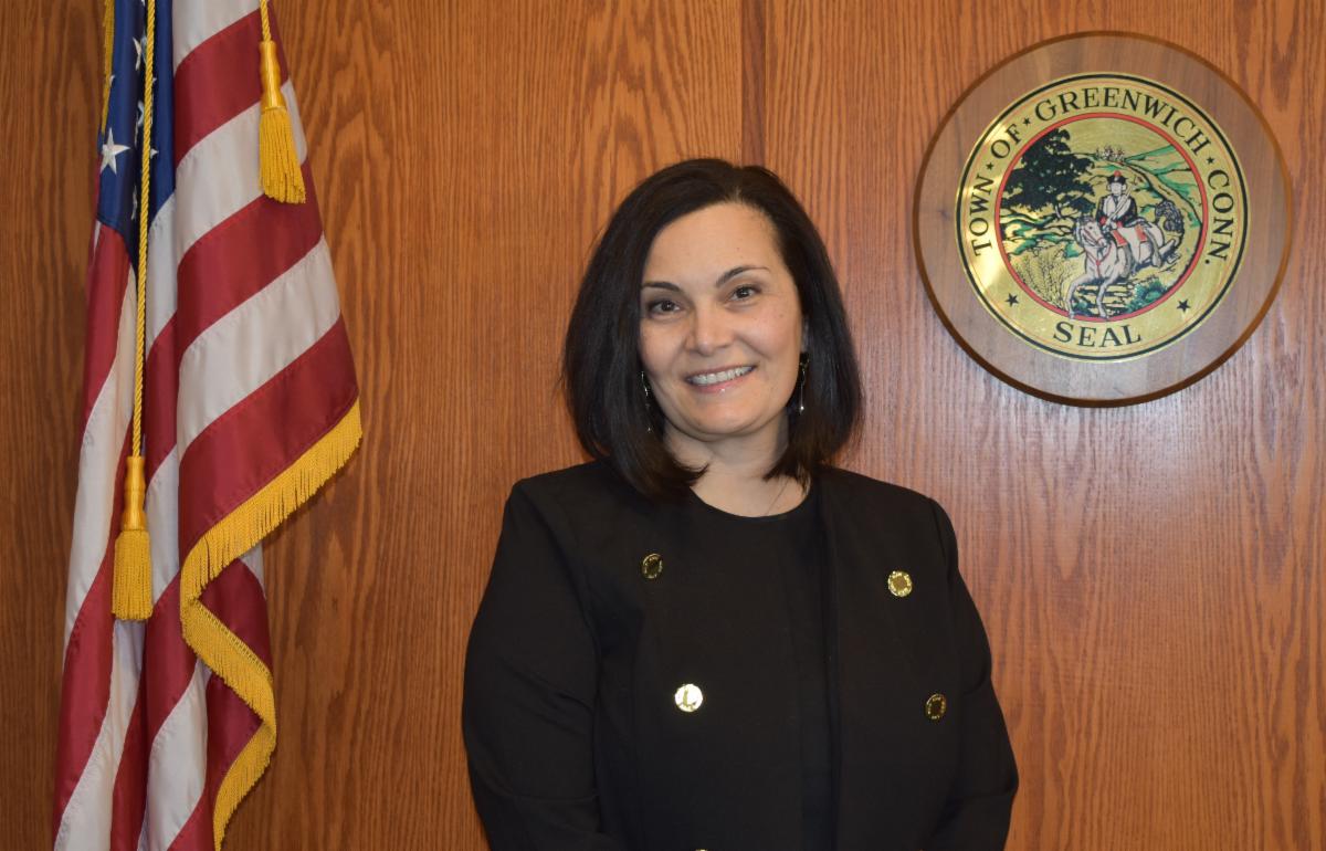 a woman standing next to an American flag and a town seal