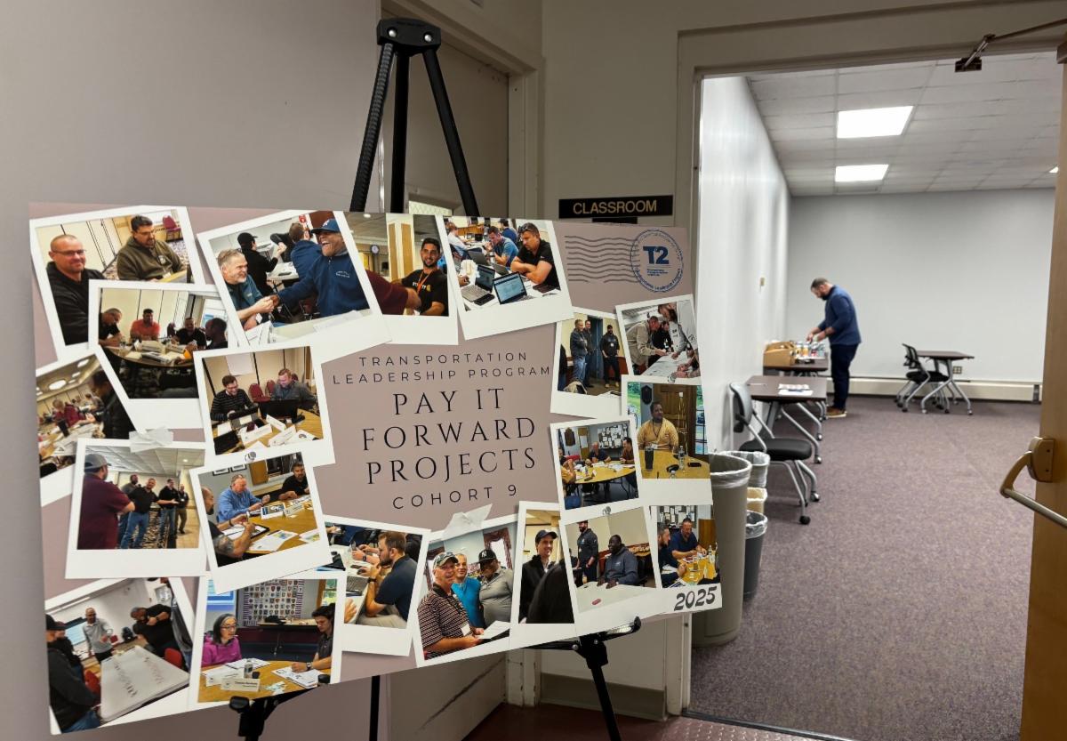 poster board on an easel showing collage of people working together with text transportation leadership program pay it forward projects cohort 9 and a person setting up in background
