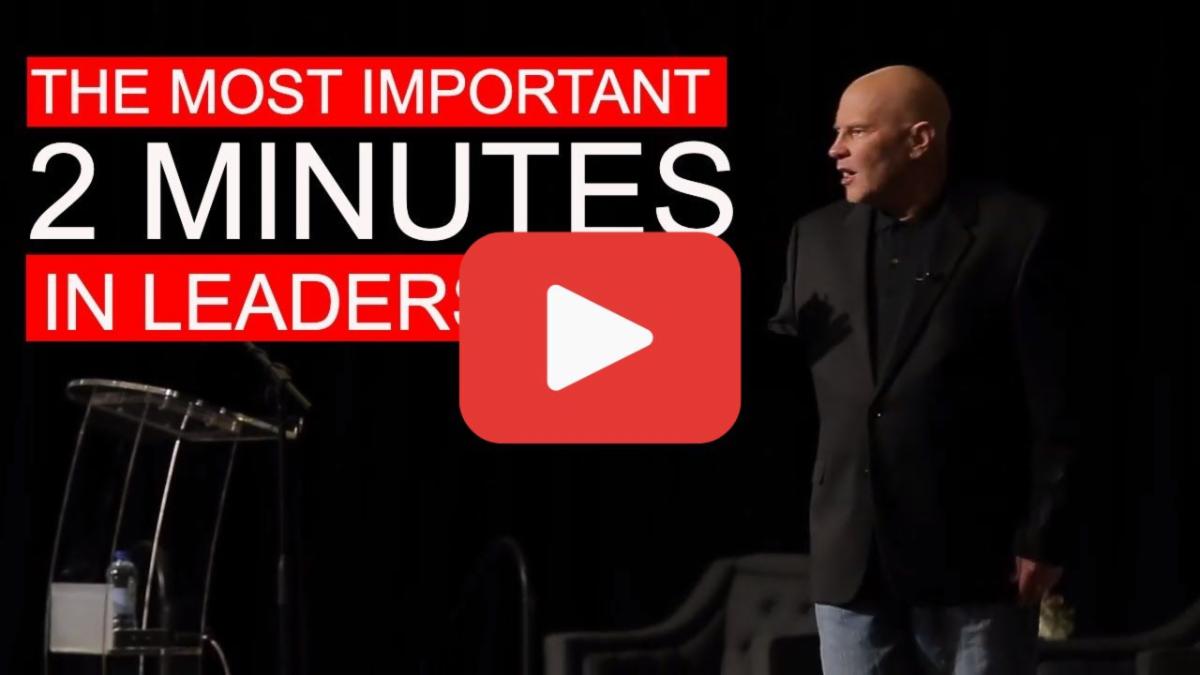 A person standing on a stage with a microphone and a YouTube play button