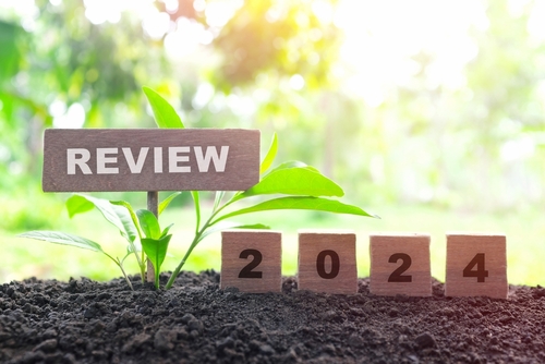 Year end 2024 review and summary concept. Wooden blocks in dark sunset on natural background.