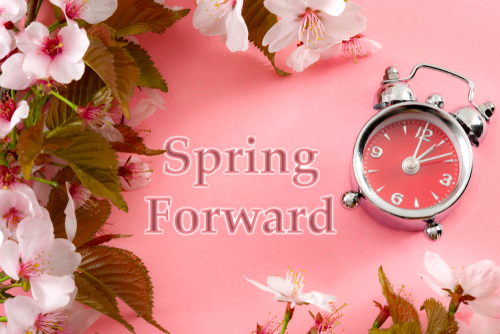 Turn clocks on hour ahead_ star of daylight savings time change and reminder to spring forward concept with alarm clock on pink background with springtime flowers and text - spring forward