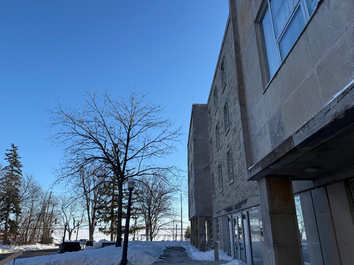 Morris Hall exterior against a blue sky with snow on the ground and Lake Ontario in the background
