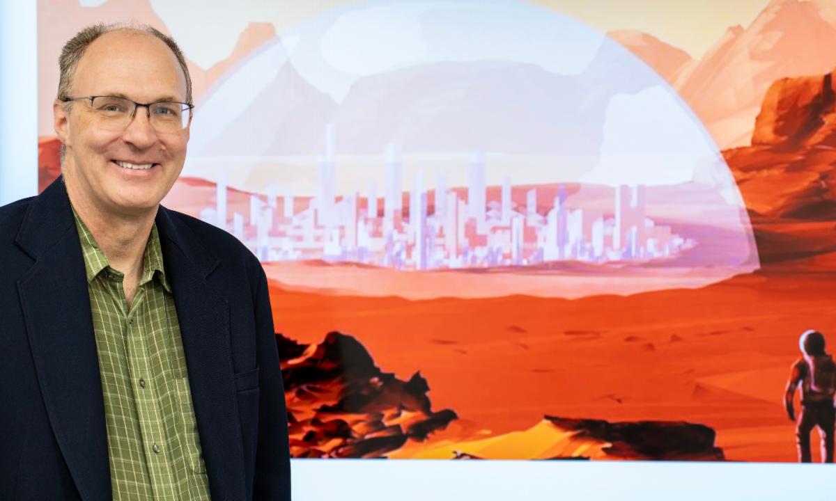 Kevin Dahm stands in front of a scene of Mars designed for game-based learning.