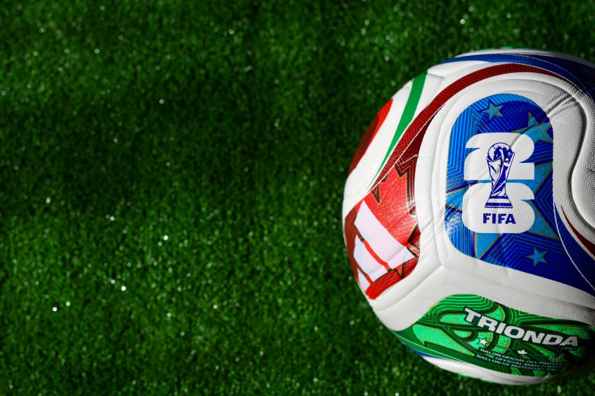 Close-up of a FIFA soccer ball on green turf, with colorful panels and logo visible.