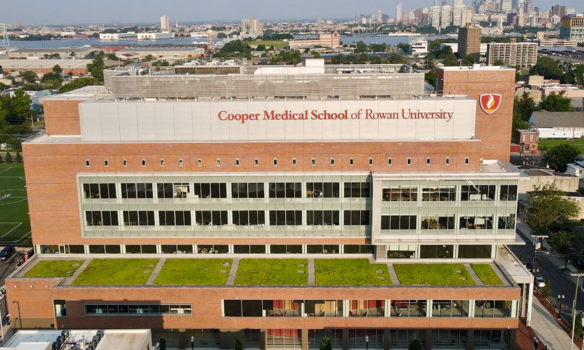 Exterior view of multistory Cooper Medical School of Rowan University building with skyline in the background.