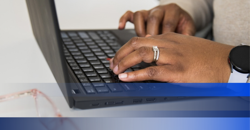 A womanâ€™s hands typing on a laptop.