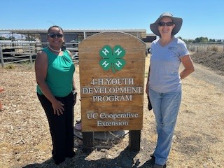 Dr. Kimberly Holmes and a California 4-H volunteer stand at the 4-H Youth Development Program sign at Homesteaders 4-H Ranch.