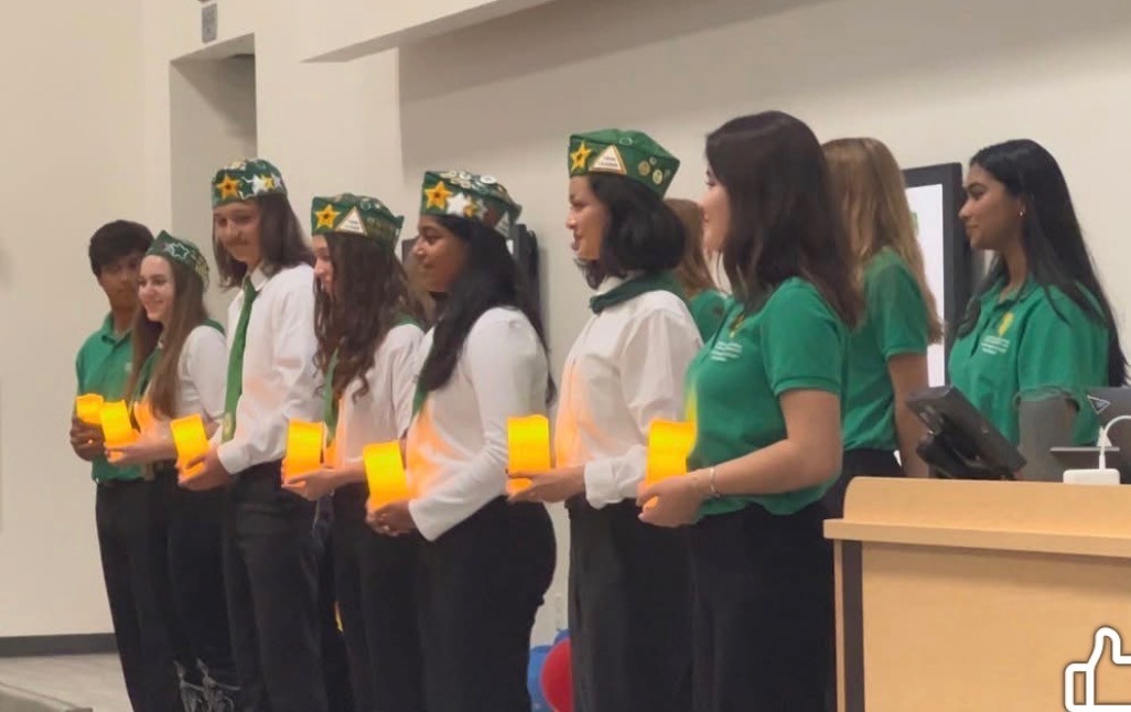 Youth dressed in 4-H shirts, ties and hats holding candles at a ceremony from the 2025 State Leadership Conference