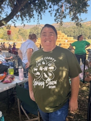 Adult in green shirt reading “Yolo County 4-H Spring Show 2025”
