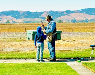 4-H Volunteer Pat Karinen with a youth in a field with hills in the background 