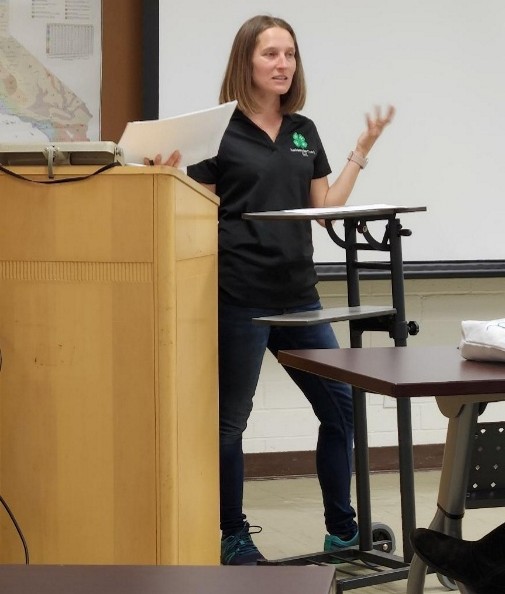 Ms. Bri Jokerst stands at a podium in a classroom setting