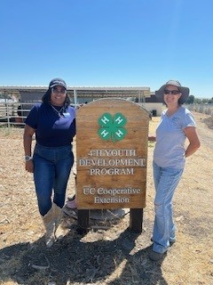  Dr. Janine Woods, Executive Director of County Cooperative Extension (statewide) and a California 4-H volunteer stand at the 4-H Youth Development Program sign at Homesteaders 4-H Ranch.