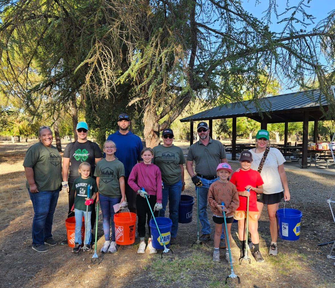Adults and youth members of Fairmont 4-H pose in front of a tree after a garbage cleanup group event.