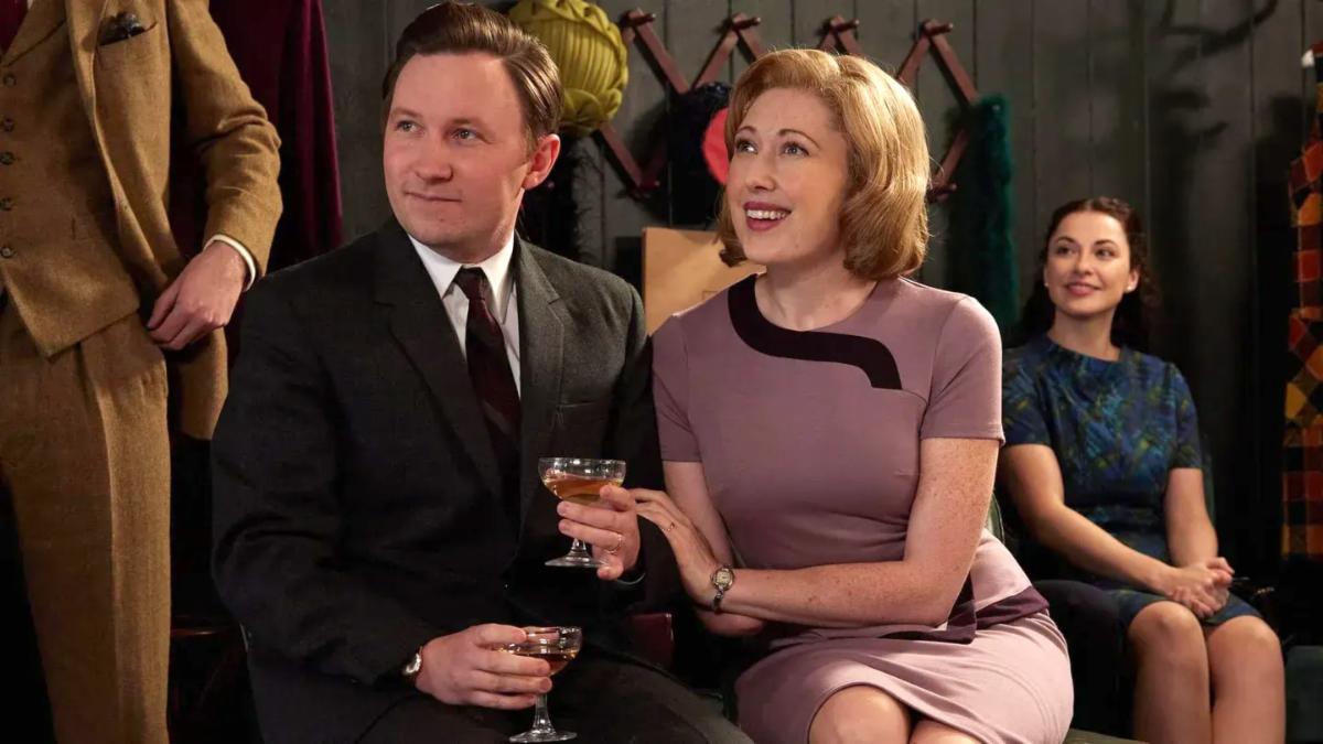 A dressed-up couple sit together while looking up and listening to someone talk