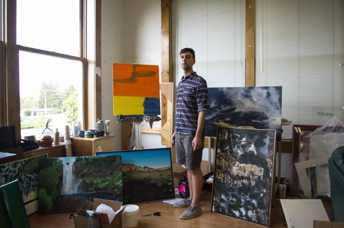 A man stands in a room with paintings 