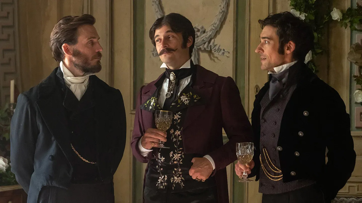 Three men in Victorian suits talk while two hold wine goblets