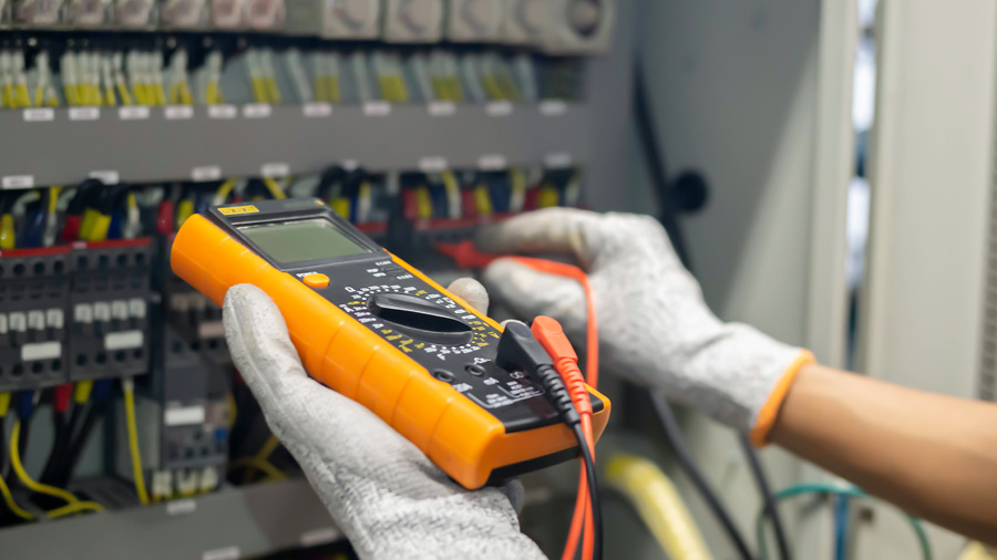 A close up of the gloved hands of an electrician checking voltage