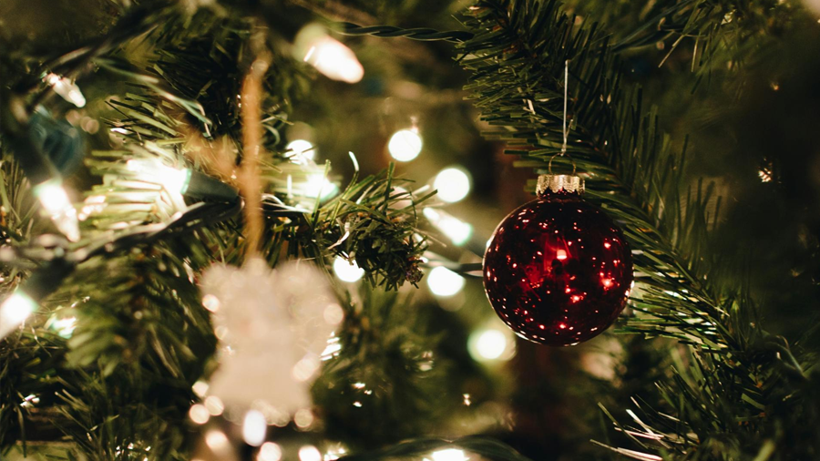 An ornament in a Christmas tree covered in lights