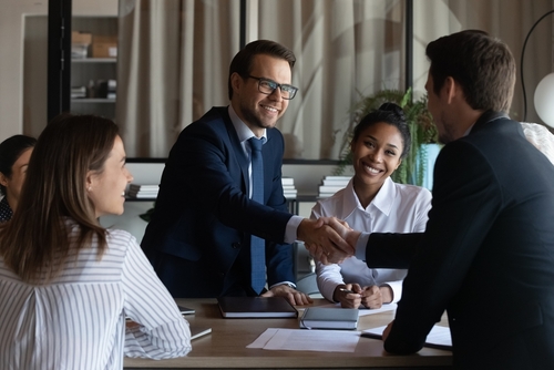 Nice to meet you in our team. Friendly man leader boss shake hand of new staff member welcome young male on job in corporate department. Professional businesspeople reached agreement on negotiations