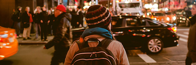 Person walking across a busy street in a busy city.